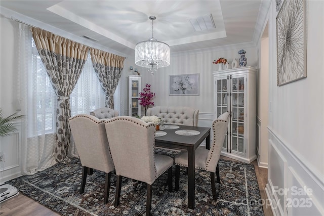 dining room featuring hardwood / wood-style flooring, a tray ceiling, and an inviting chandelier