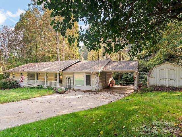 single story home featuring a carport, a storage shed, a porch, and a front yard