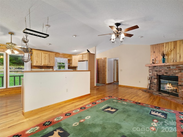 interior space featuring light wood-type flooring, lofted ceiling, ceiling fan, and a fireplace