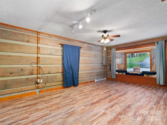 229 Medford Hannah Rd, Waynesville, NC 28785 - empty room with a textured ceiling, wood finished floors, a ceiling fan, a baseboard radiator, and wood walls