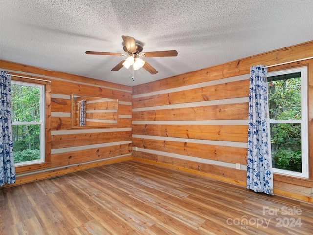 spare room featuring ceiling fan, hardwood / wood-style flooring, plenty of natural light, and a textured ceiling