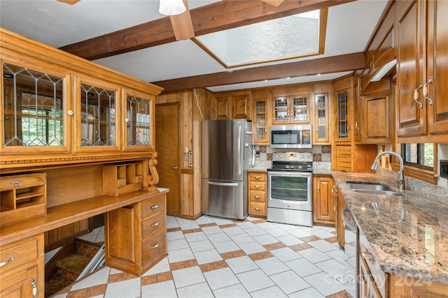 kitchen featuring appliances with stainless steel finishes, light stone counters, sink, light tile patterned floors, and beam ceiling