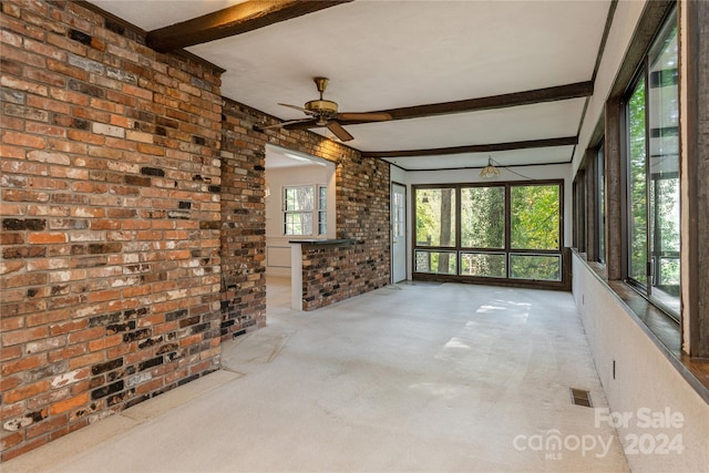 interior space featuring beam ceiling, light colored carpet, ceiling fan, and brick wall