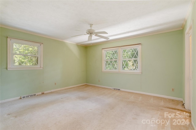 spare room with ceiling fan, a healthy amount of sunlight, light colored carpet, and ornamental molding