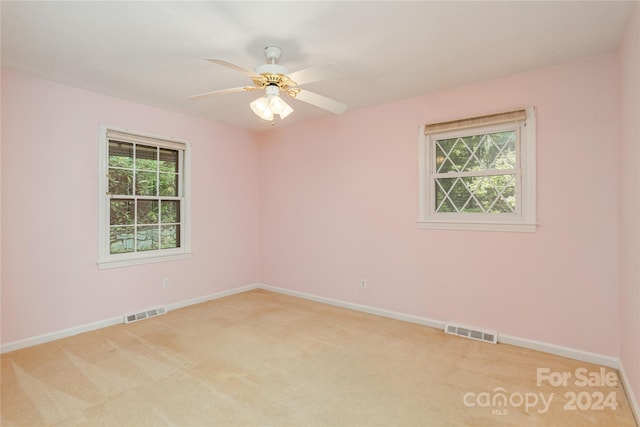 empty room featuring ceiling fan, a healthy amount of sunlight, and light carpet