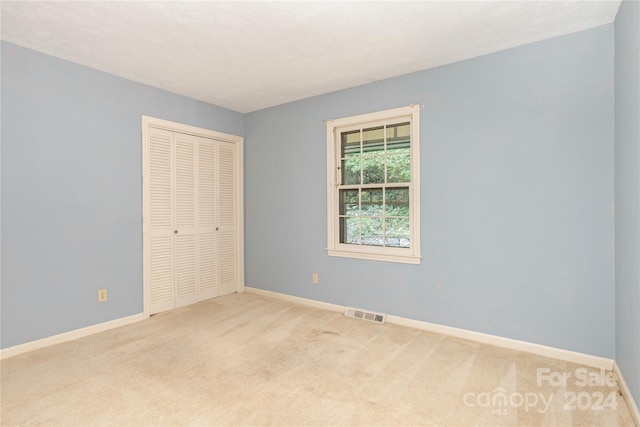 unfurnished bedroom with light carpet and a closet