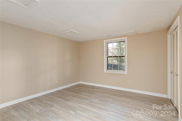 1010 Indian Hill Rd, Hendersonville, NC 28791 - unfurnished bedroom featuring attic access, light wood-style flooring, baseboards, a closet, and a textured ceiling