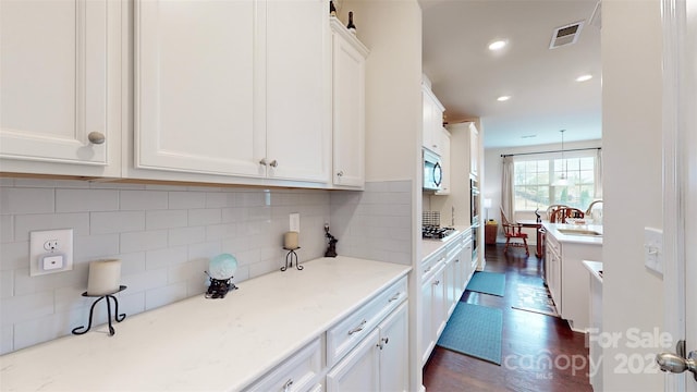 kitchen featuring pendant lighting, white cabinets, sink, tasteful backsplash, and stainless steel appliances