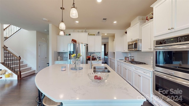 kitchen featuring sink, a center island with sink, white cabinets, and appliances with stainless steel finishes