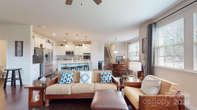 living room with ceiling fan, sink, and dark wood-type flooring