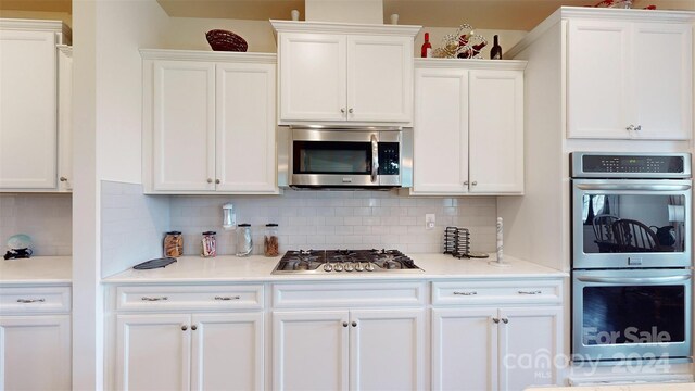 kitchen with decorative backsplash, appliances with stainless steel finishes, and white cabinetry