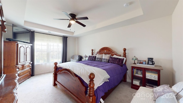 carpeted bedroom featuring ceiling fan and a tray ceiling