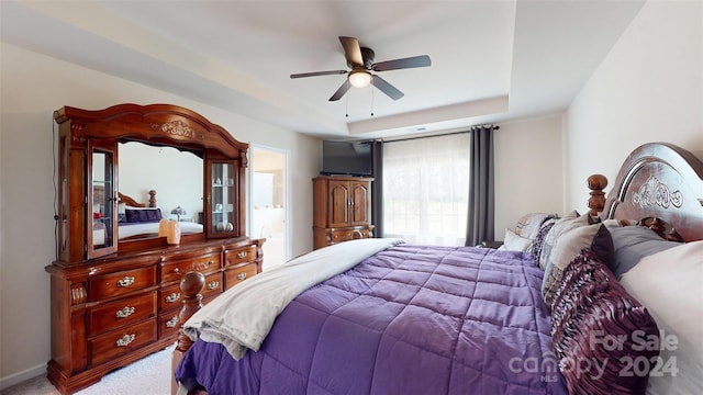 bedroom featuring a tray ceiling, ceiling fan, and light carpet