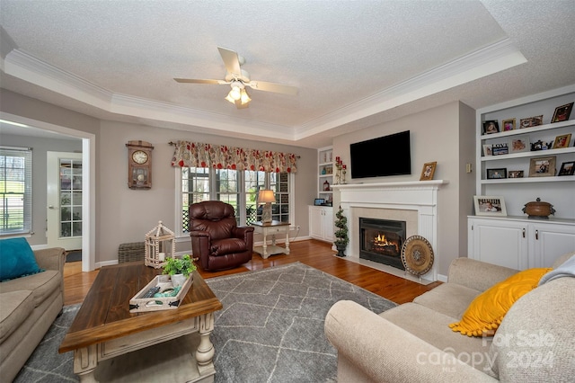 living room with a textured ceiling, dark hardwood / wood-style flooring, and a tray ceiling