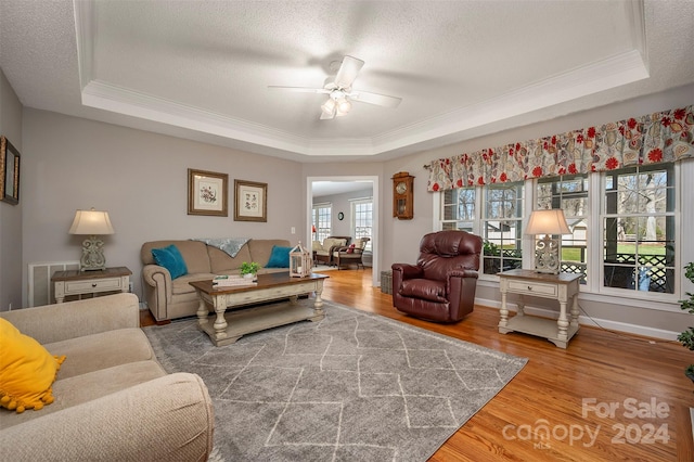 living room featuring wood-type flooring, a healthy amount of sunlight, and a tray ceiling