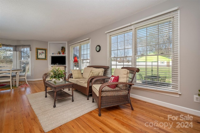 living area with plenty of natural light, light wood-type flooring, and a textured ceiling