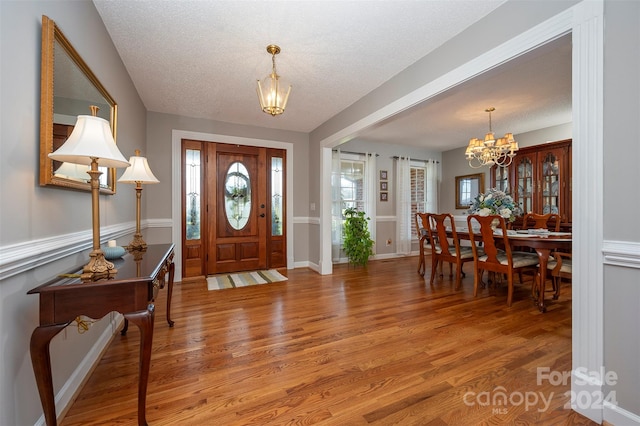 entryway with a chandelier, hardwood / wood-style floors, and a textured ceiling