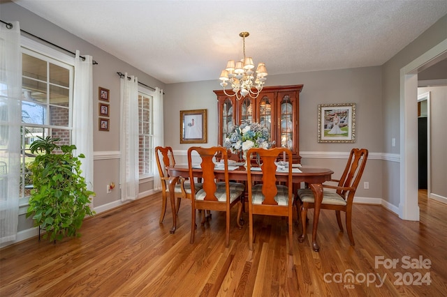 dining room featuring a textured ceiling, a notable chandelier, and hardwood / wood-style flooring