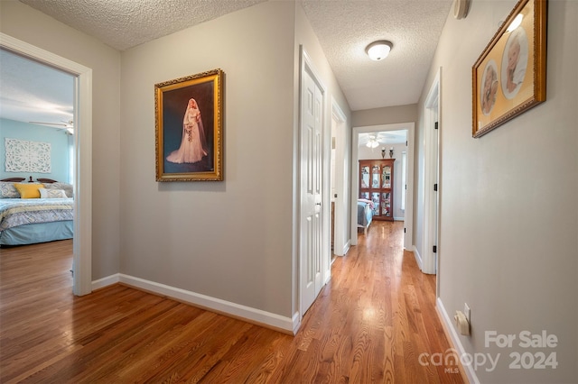 corridor with a textured ceiling and hardwood / wood-style flooring