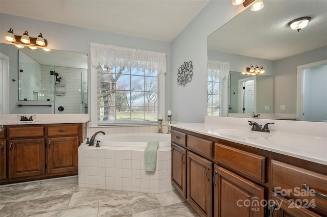 bathroom featuring shower with separate bathtub, vanity, and a textured ceiling