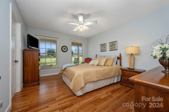 bedroom featuring ceiling fan, wood-type flooring, and a textured ceiling