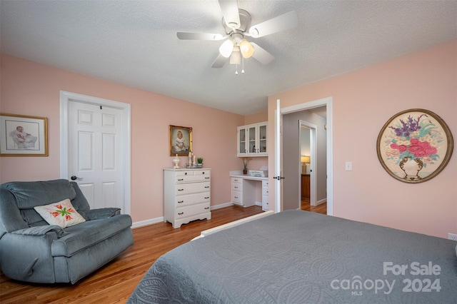 bedroom with a textured ceiling, light wood-type flooring, and ceiling fan