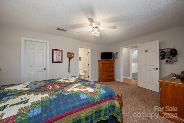 carpeted bedroom with a textured ceiling, ceiling fan, and ensuite bath