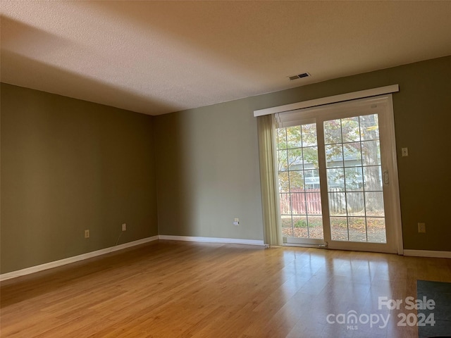 spare room featuring light hardwood / wood-style floors and a textured ceiling