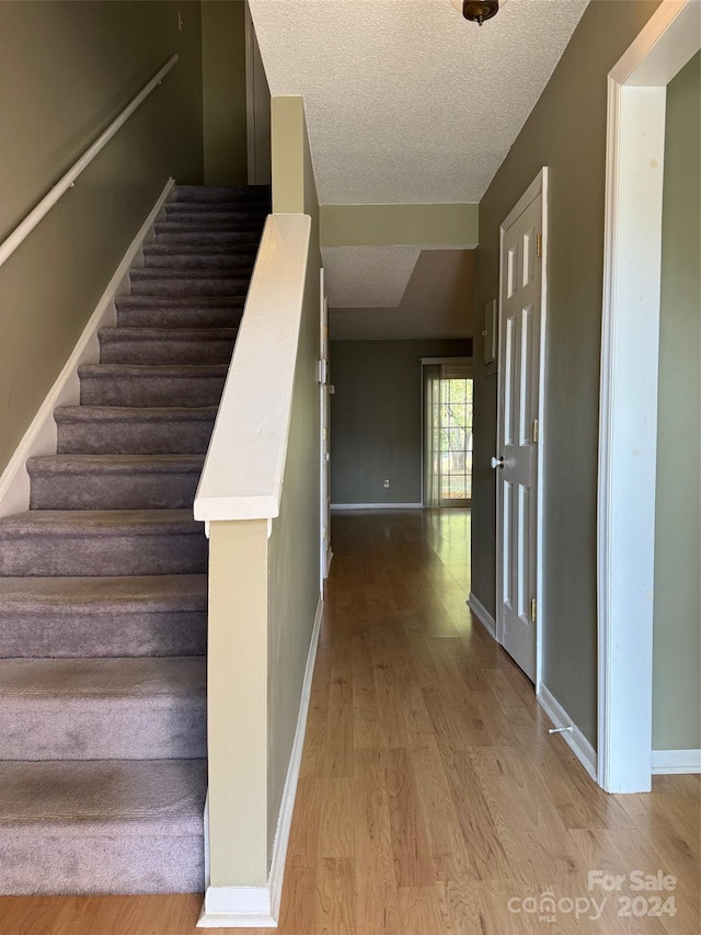 staircase featuring hardwood / wood-style floors and a textured ceiling