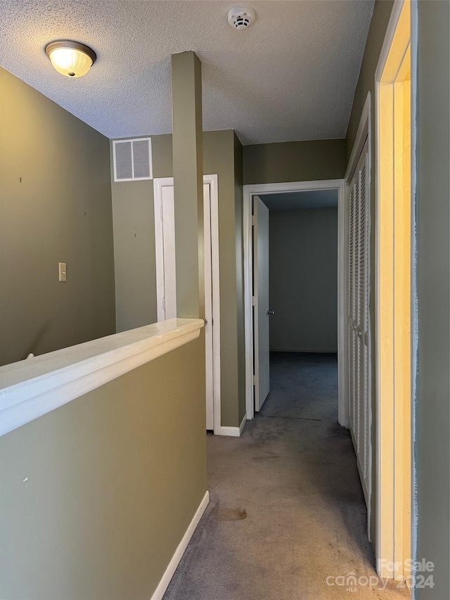 hall featuring carpet and a textured ceiling