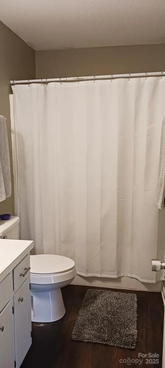 bathroom featuring a textured ceiling, vanity, hardwood / wood-style flooring, and toilet