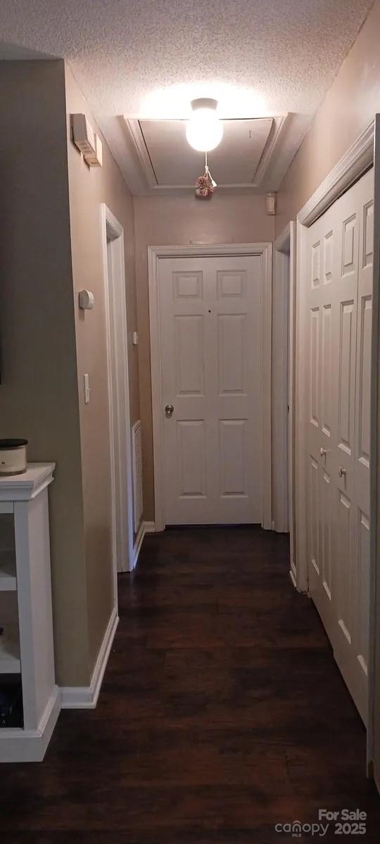 corridor featuring dark hardwood / wood-style floors and a textured ceiling