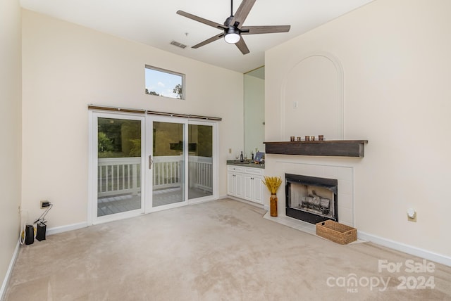 unfurnished living room featuring a fireplace, light carpet, and ceiling fan