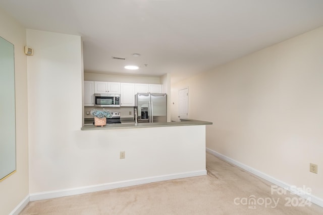 kitchen featuring kitchen peninsula, light carpet, stainless steel appliances, and white cabinets