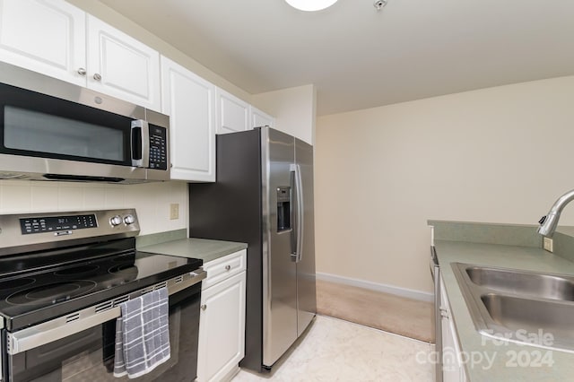 kitchen with white cabinets, appliances with stainless steel finishes, tasteful backsplash, and sink