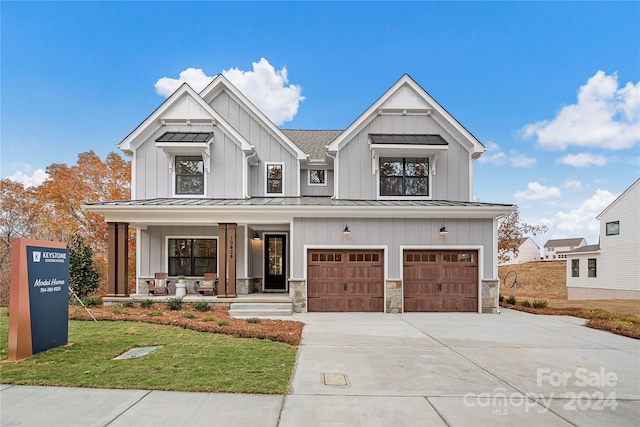 modern inspired farmhouse with a front lawn, a garage, and covered porch