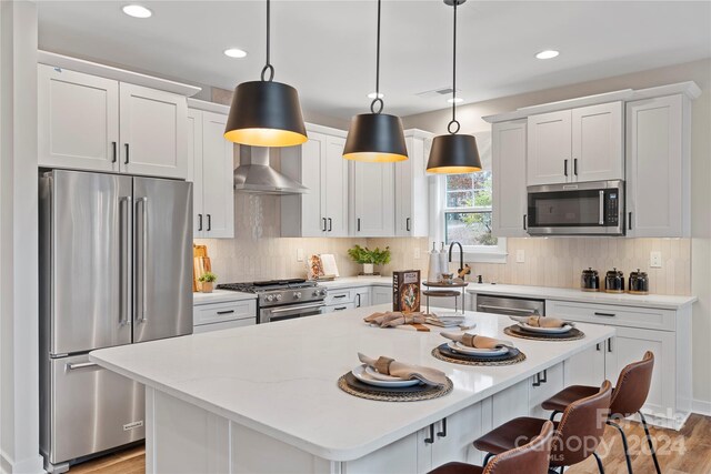 kitchen with high end appliances, a center island, white cabinets, and decorative light fixtures