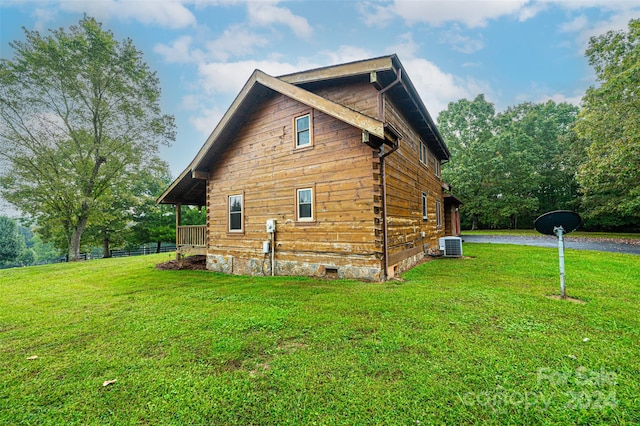 view of side of property featuring a lawn and central AC