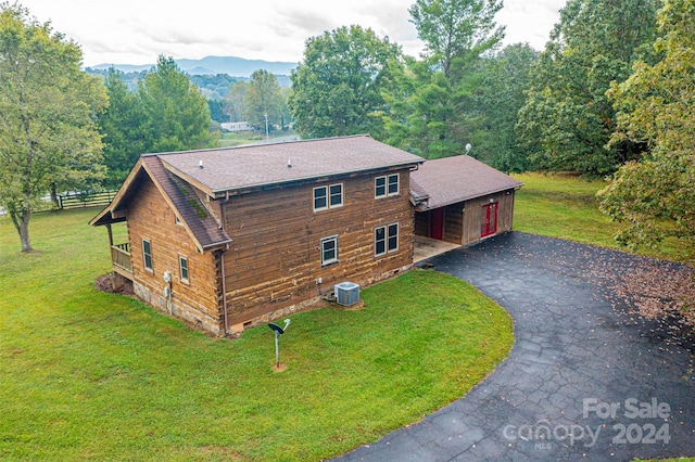 exterior space featuring a front yard, a mountain view, and cooling unit