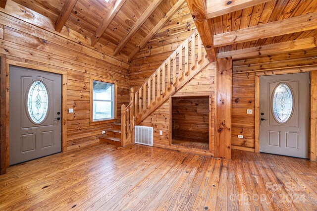 entrance foyer featuring wood ceiling, wood walls, lofted ceiling with beams, and light hardwood / wood-style flooring