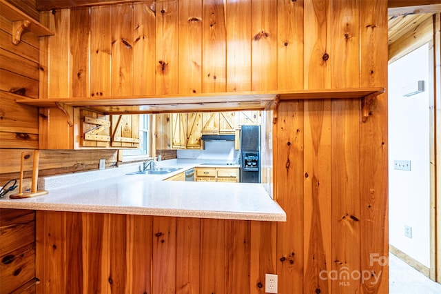 kitchen featuring kitchen peninsula, wooden walls, sink, and stovetop