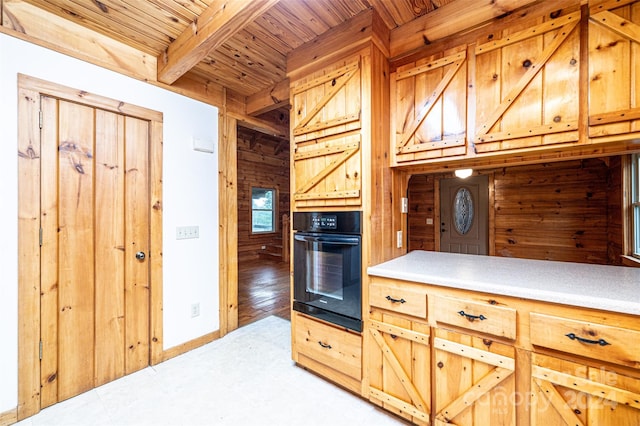 kitchen with wood walls, black oven, wooden ceiling, beam ceiling, and hardwood / wood-style flooring