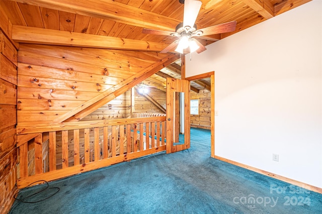 spare room featuring carpet flooring, wooden walls, vaulted ceiling with beams, ceiling fan, and wooden ceiling