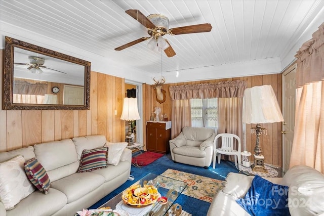 carpeted living room with ceiling fan and wood walls