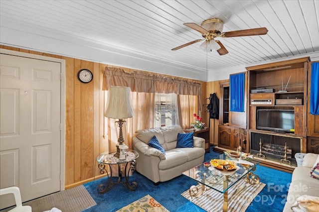 carpeted living room with wood walls, wood ceiling, and ceiling fan