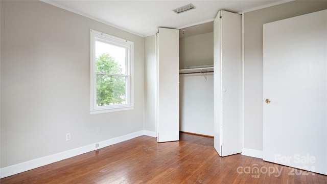 unfurnished bedroom featuring crown molding, hardwood / wood-style flooring, and a closet