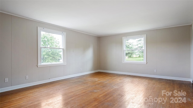 spare room featuring crown molding, hardwood / wood-style flooring, and a healthy amount of sunlight