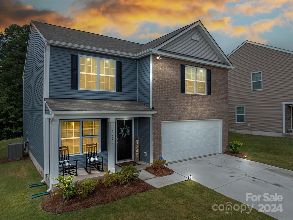 view of front of house featuring a lawn, central AC unit, and a garage