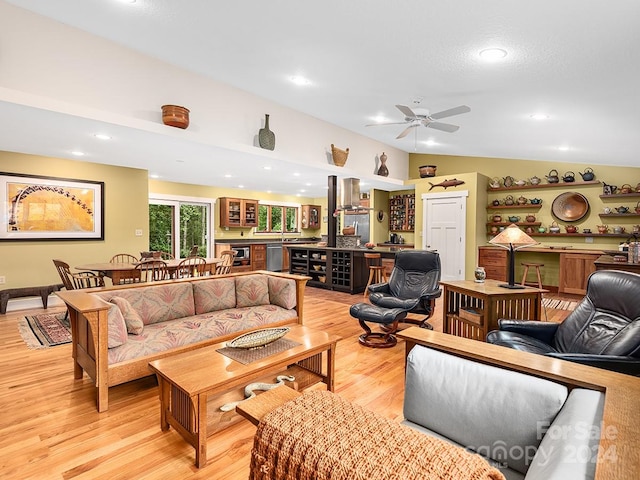 living room with light hardwood / wood-style flooring, lofted ceiling, and ceiling fan