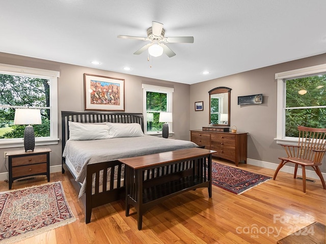 bedroom with ceiling fan, multiple windows, and hardwood / wood-style floors